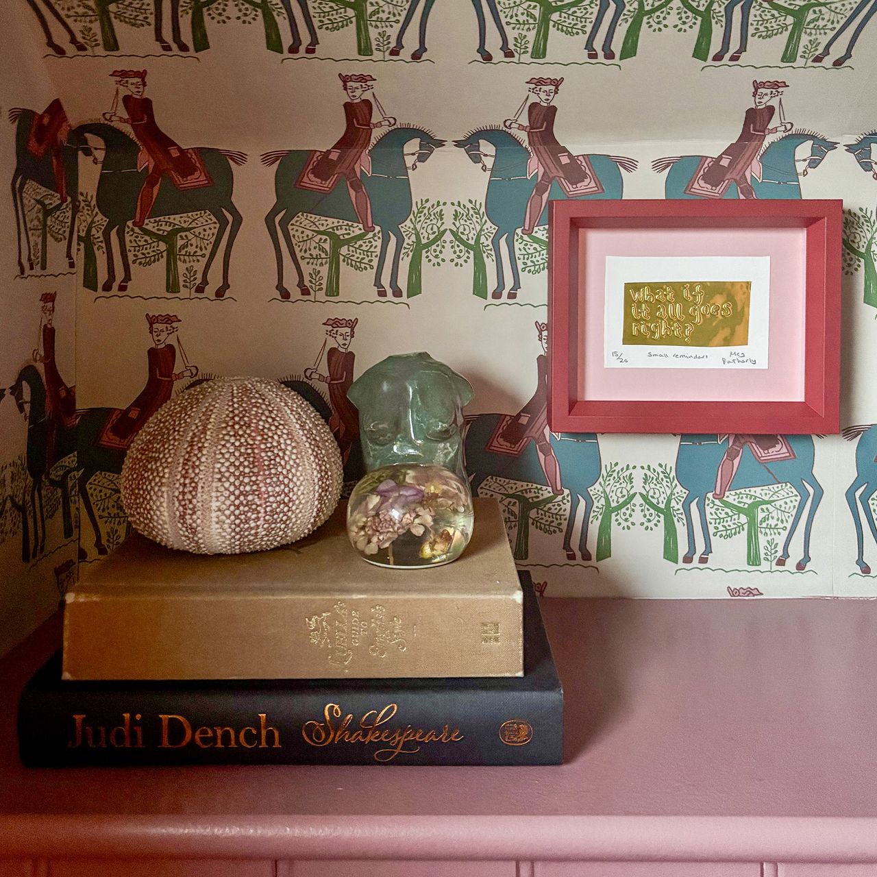 pink shelf styled with two books, a shell and some ornaments