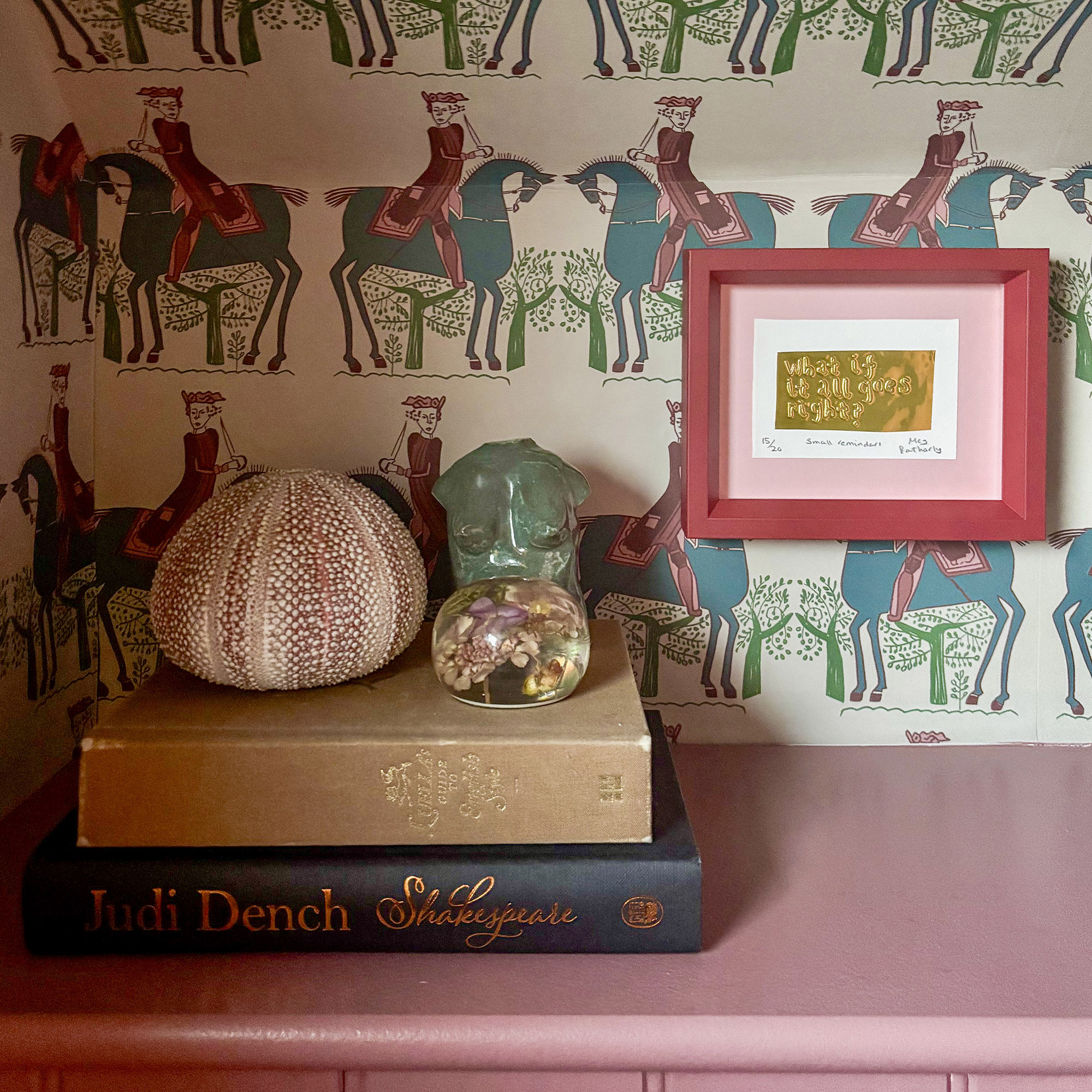 pink shelf styled with two books, a shell and some ornaments