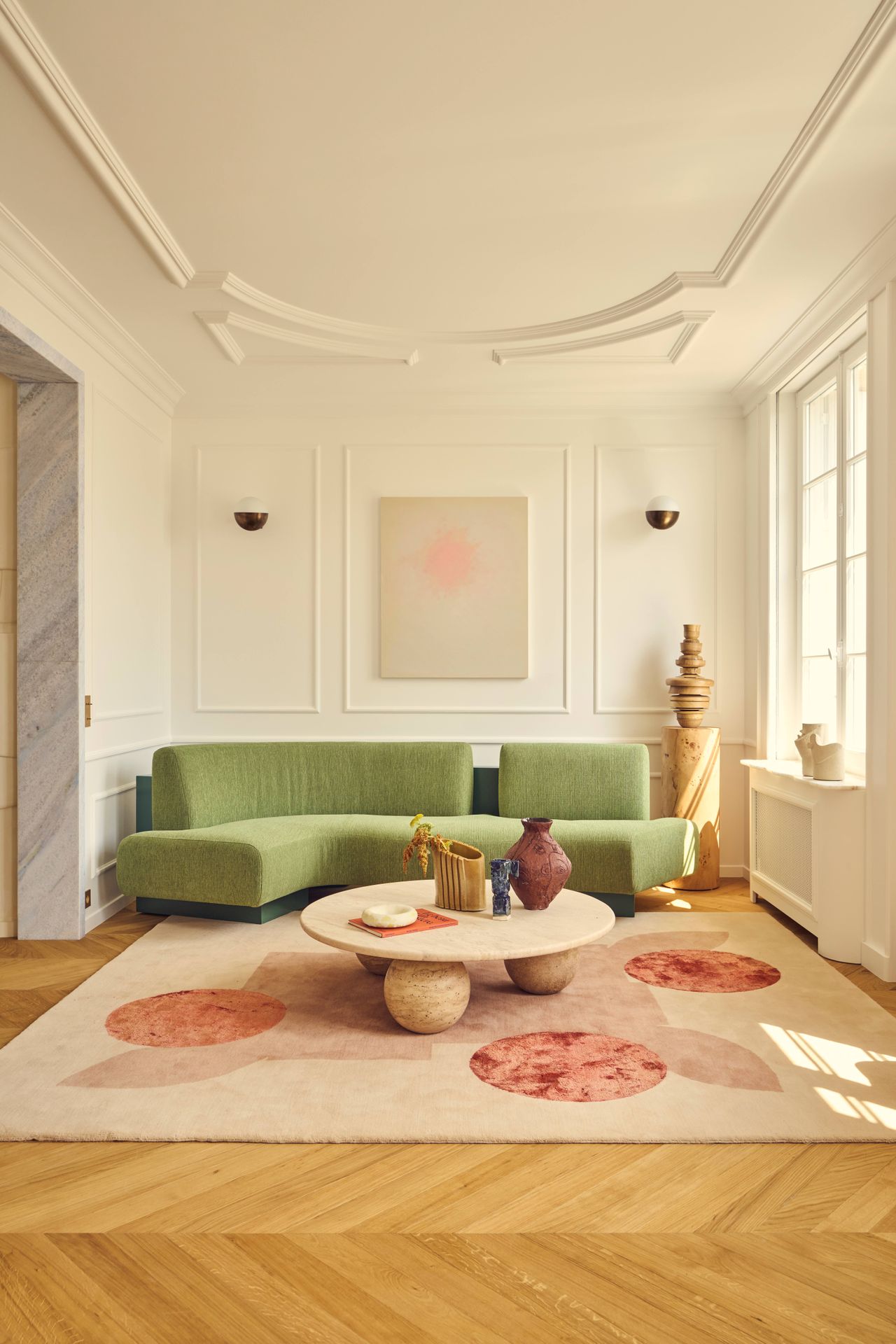Batiik Studio-designed living room / dining room combo area featuring peachy pastel pinks, herringbone floors, sculptural custom made furniture, and an original fireplace.