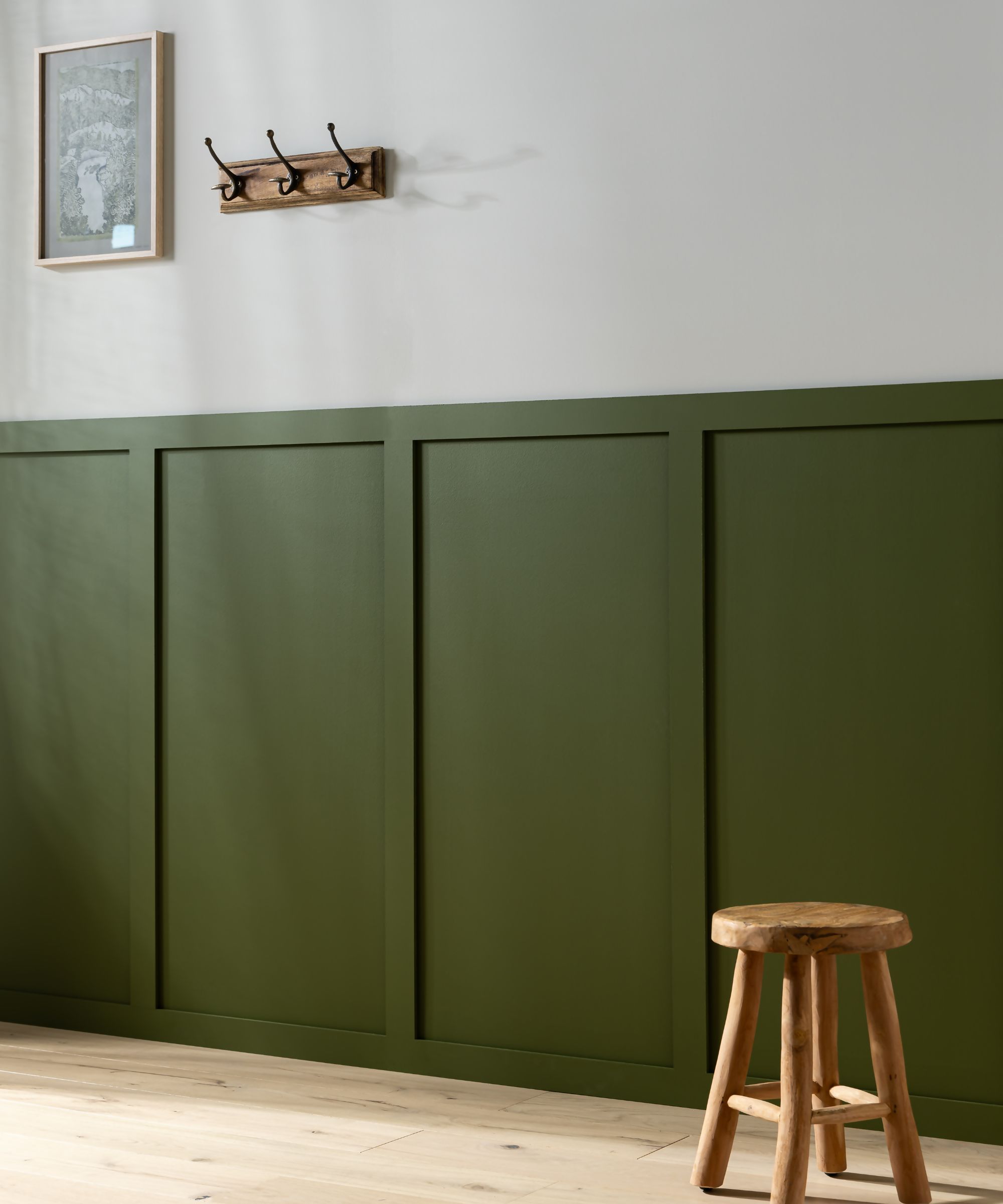 Green half-wall hallway panels with a small wooden bench and coat hooks above them