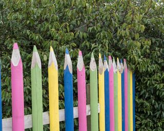 A colourful fence with posts shaped and stylised as pencils