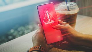 A person holding a phone with a malware warning on screen
