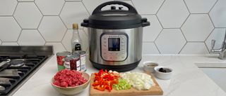 An Instant Pot Duo Nova surrounded by ingredients for a beef chilli