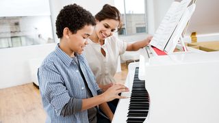 Woman and boy sit at a white piano