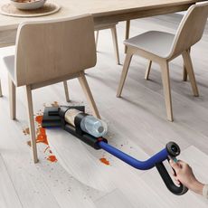 Dyson WashG1 wet floor cleaner cleaning up a tomato splatter under a chair