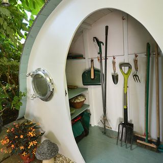 hobbit house with white wall and farming tool and potted plants