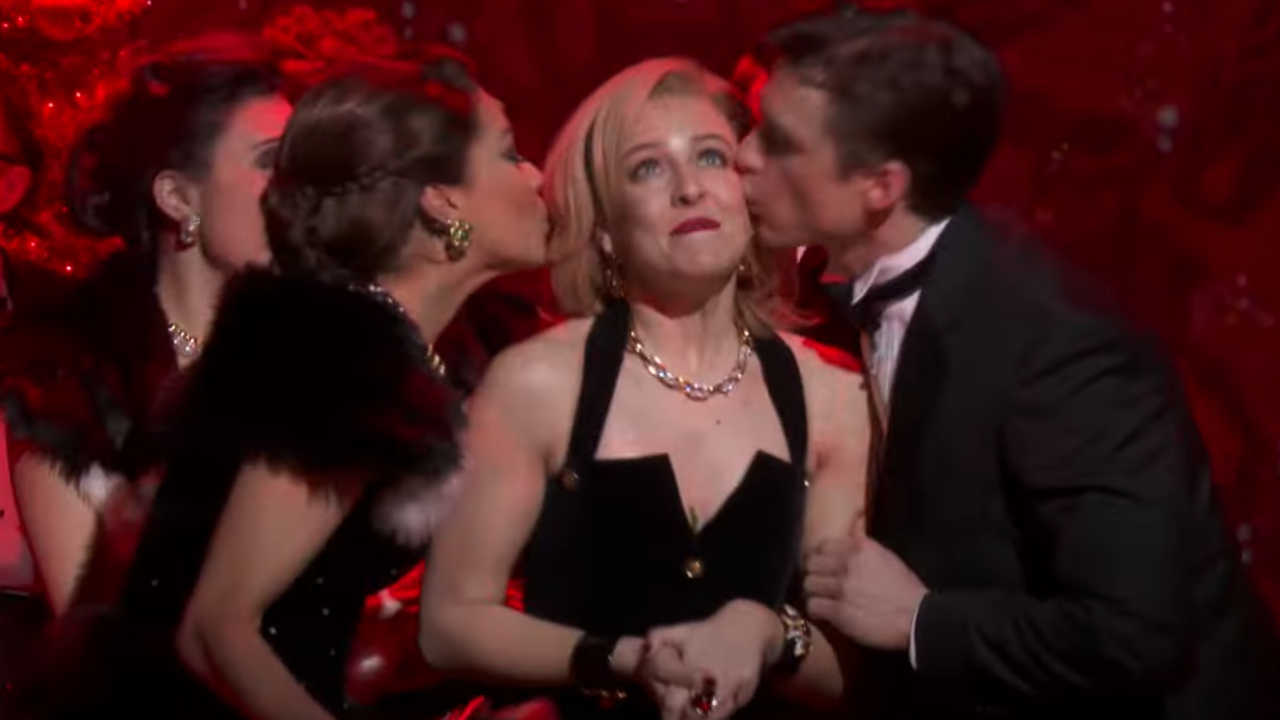 Helene Yorke smiles as she's kissed on her cheeks by two guests in American Psycho: The Musical.
