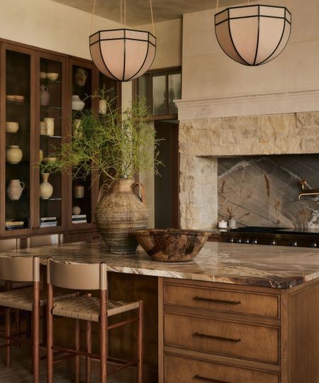 A warm neutral kitchen in Arizona with wooden micro shaker cabinets and drawers, a wall of glass cabinets, and a stone range surround