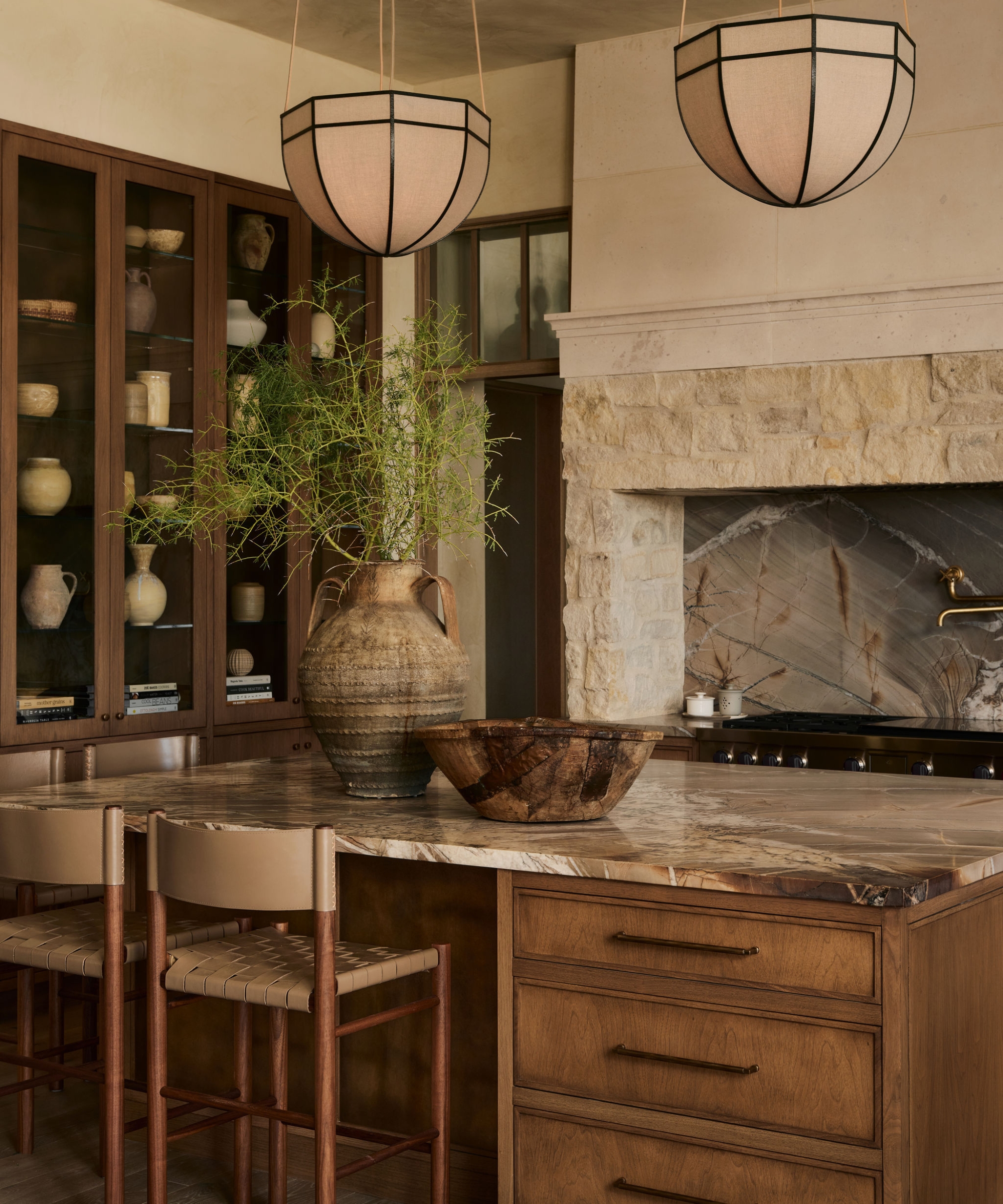 A warm neutral kitchen in Arizona with wooden micro shaker cabinets and drawers, a wall of glass cabinets, and a stone range surround