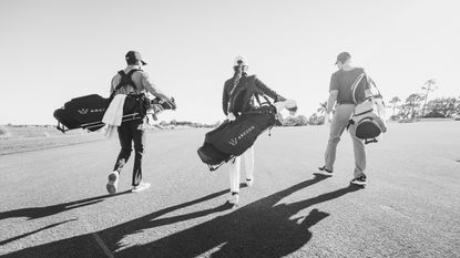 Golfers walk down the fairway carrying their bags