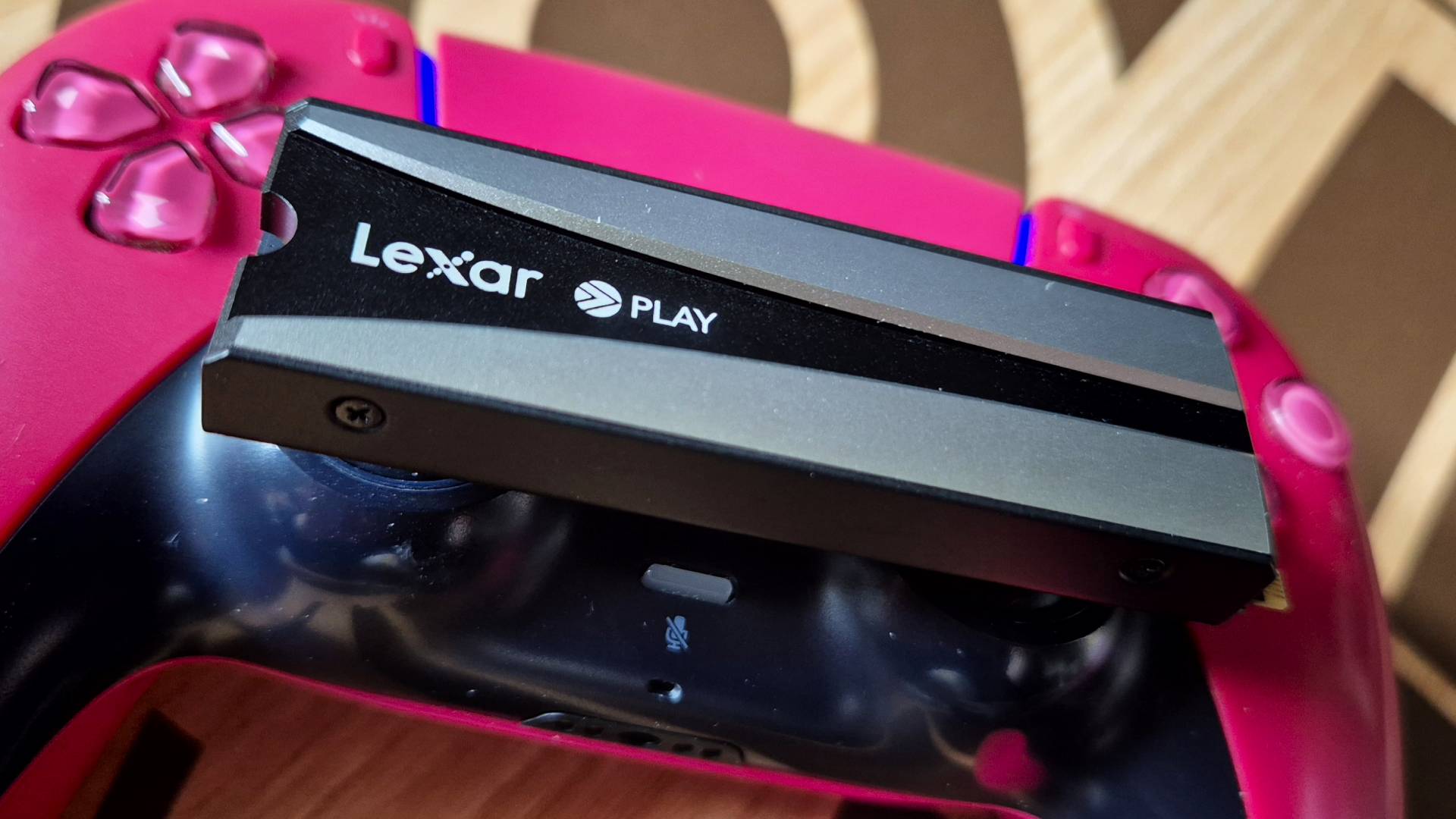 Photo by Rosalie Newcombe of the Lexar PLAY 2280 SSD sitting on top of a red PS5 DualSense controller.