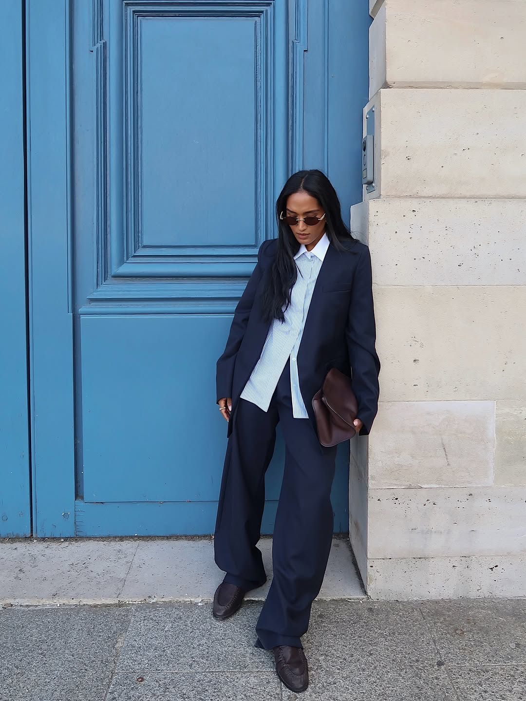 Influencer Div Ravindran wearing an anti-trend outfit of navy suit, striped shirt and loafers.
