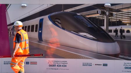 An HS2 train and a construction worker in high-visibility clothing at Euston station