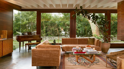 a mid-century living room with two mohair couches, a glass coffee table, wood paneled walls, and a white ceiling