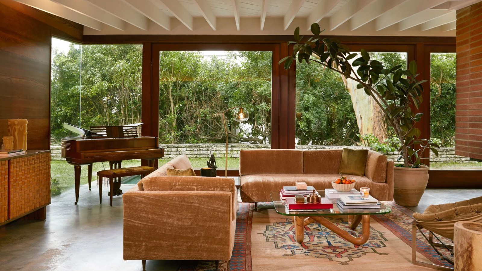 a mid-century living room with two mohair couches, a glass coffee table, wood paneled walls, and a white ceiling