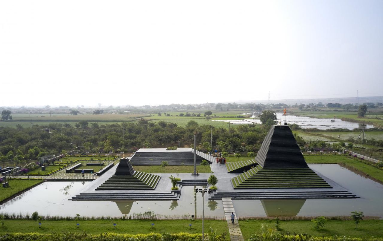 Temple of Steps called Andhra Pradesh in India, photographed from higher ground. We see three structures, in a vague pyramid shape that looks like a stacked stone plate. They&#039;re surrounded by a body of water.