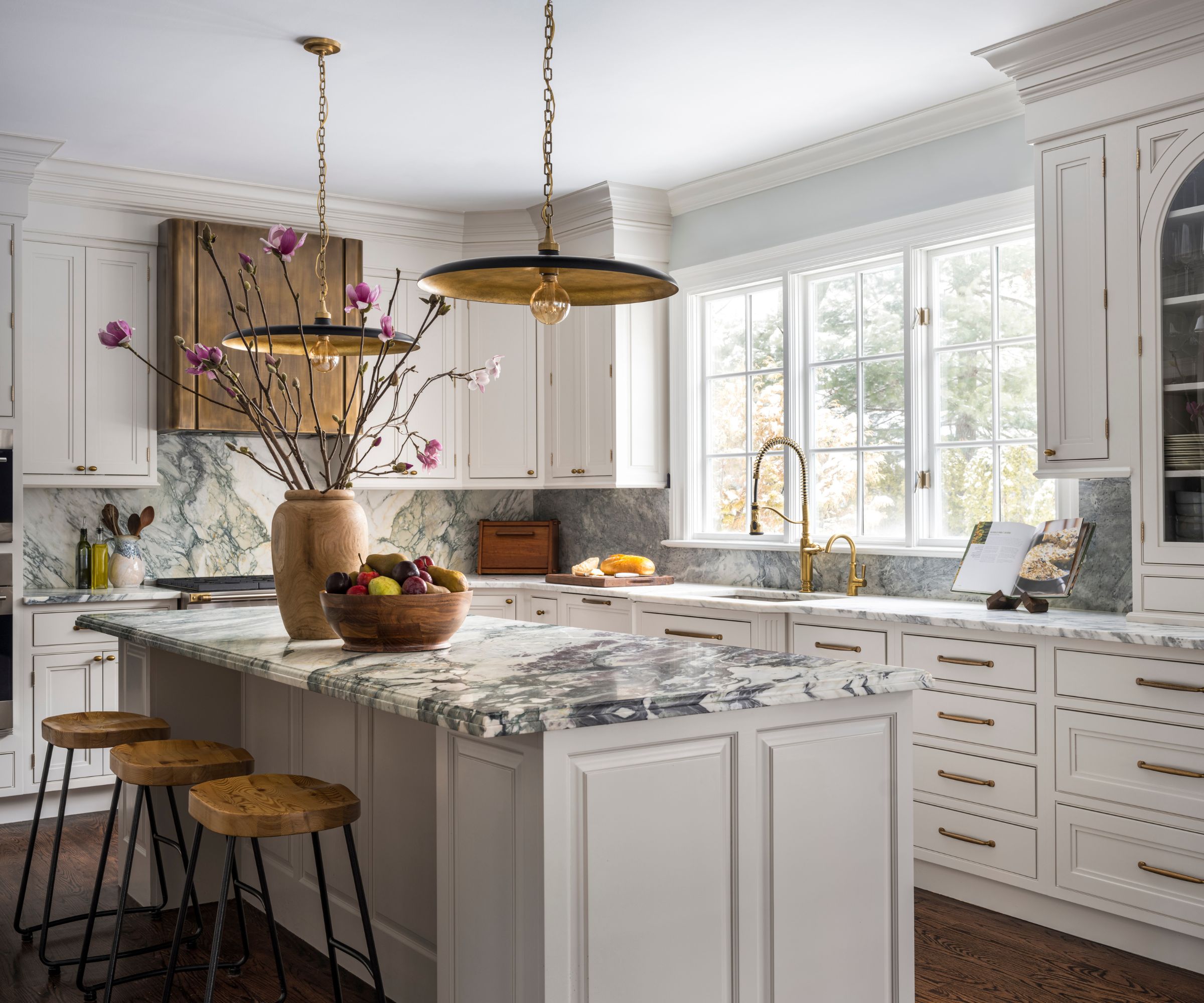 A white shaker kitchen with marble countertops and brass hardware