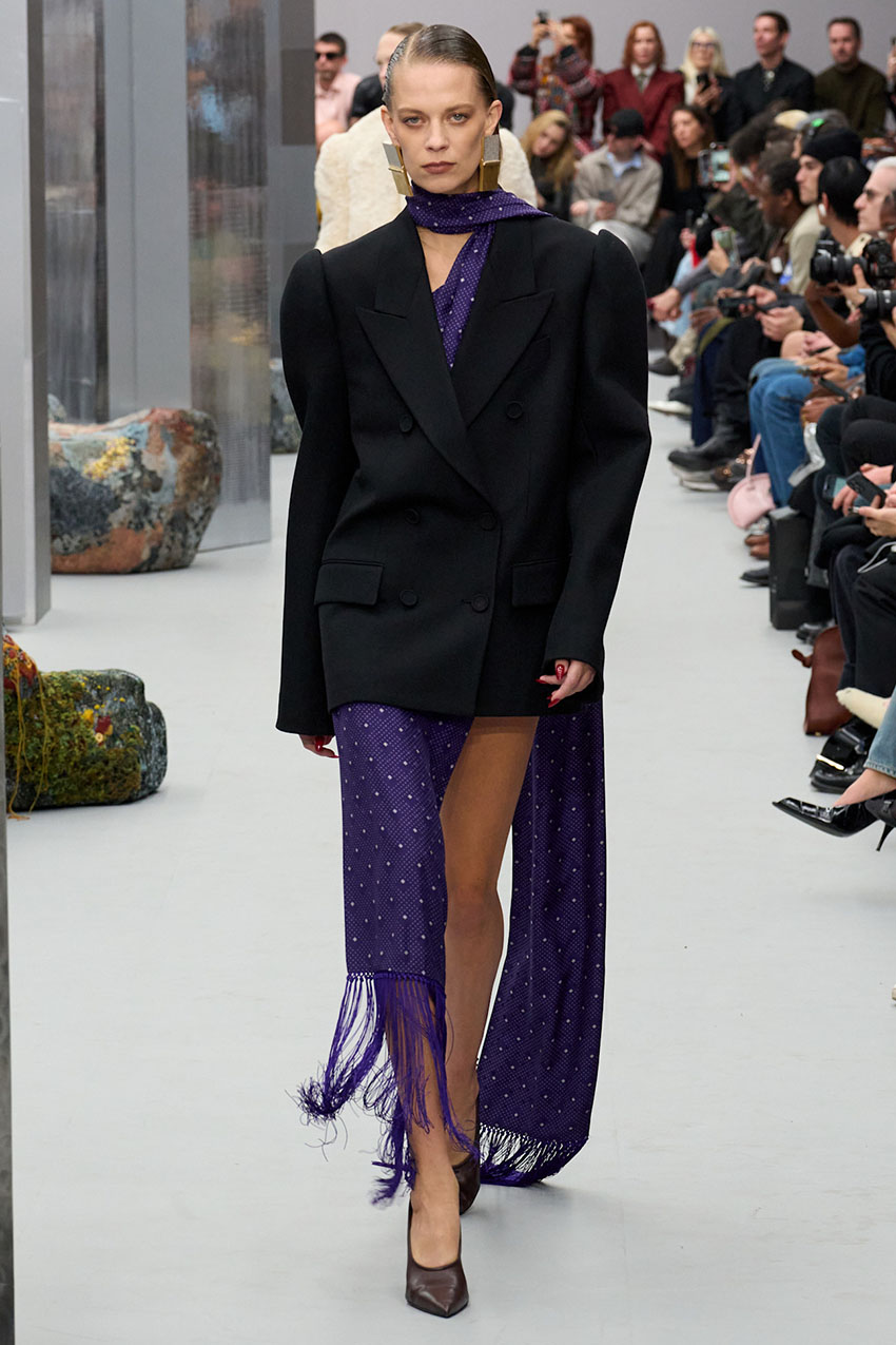An Acne Studios model wearing an overzised black blazer and purple polka dot scarf