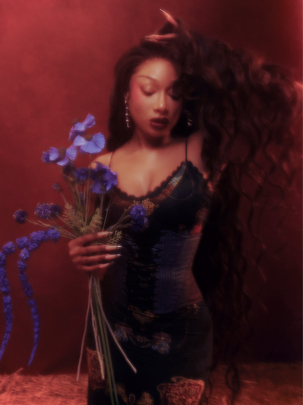 Megan Thee Stallion holding purple flowers and wearing a black dress