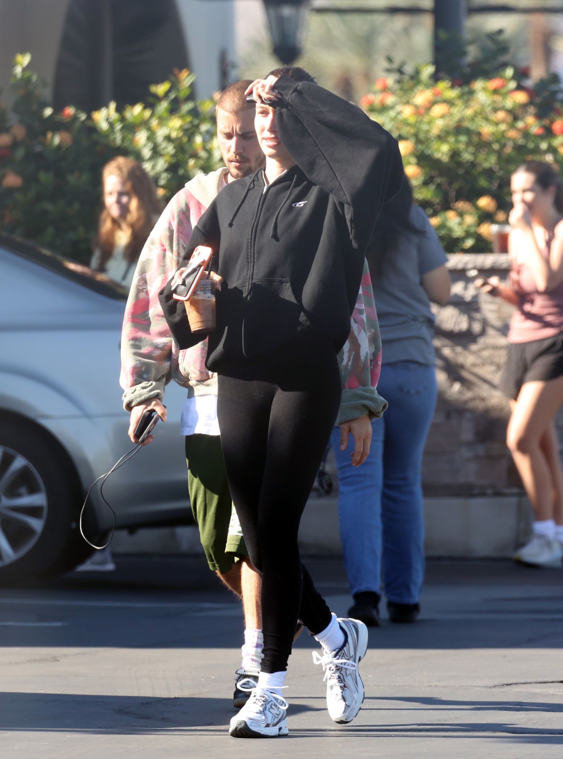 Hailey bieber wears a black zip-up sweater, black leggings, and new balance 740 sneakers.