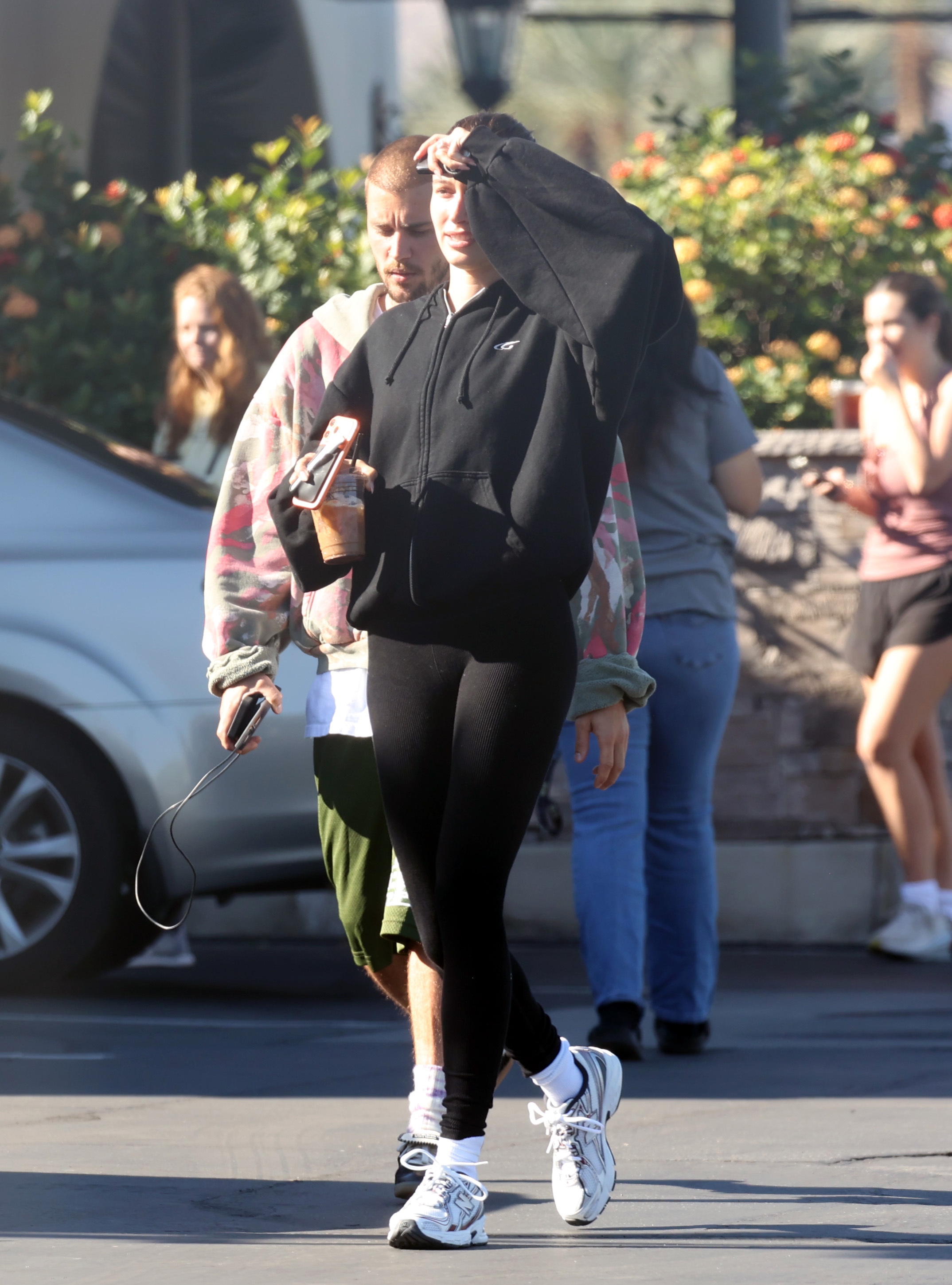 Hailey bieber wears a black zip-up sweater, black leggings, and new balance 740 sneakers.