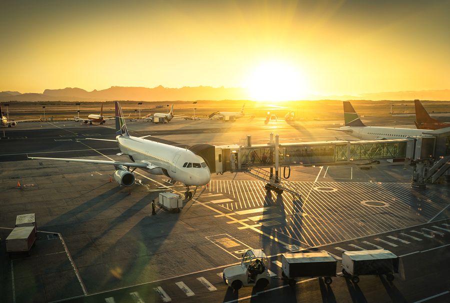 Airplane parked at gate at airport at sunset