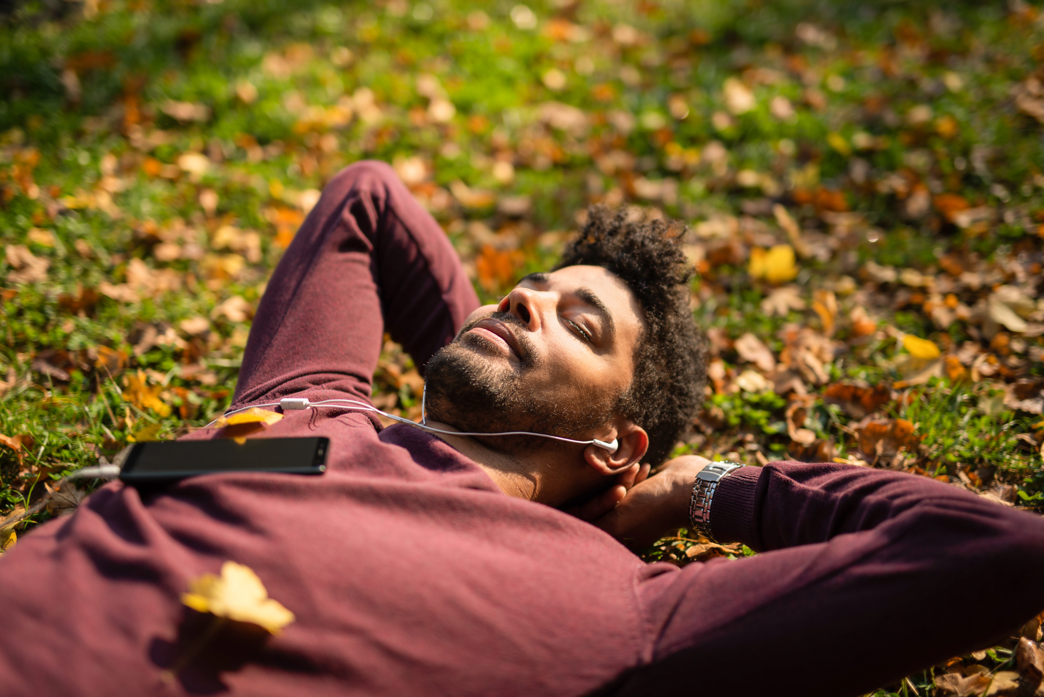 Man lying on grass with eyes closed and headphones on