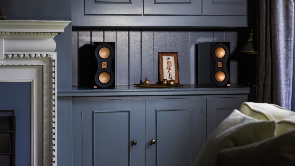 Monitor Audio Studio 89 bookshelf speakers sitting on blue shelf in lifestyle setting