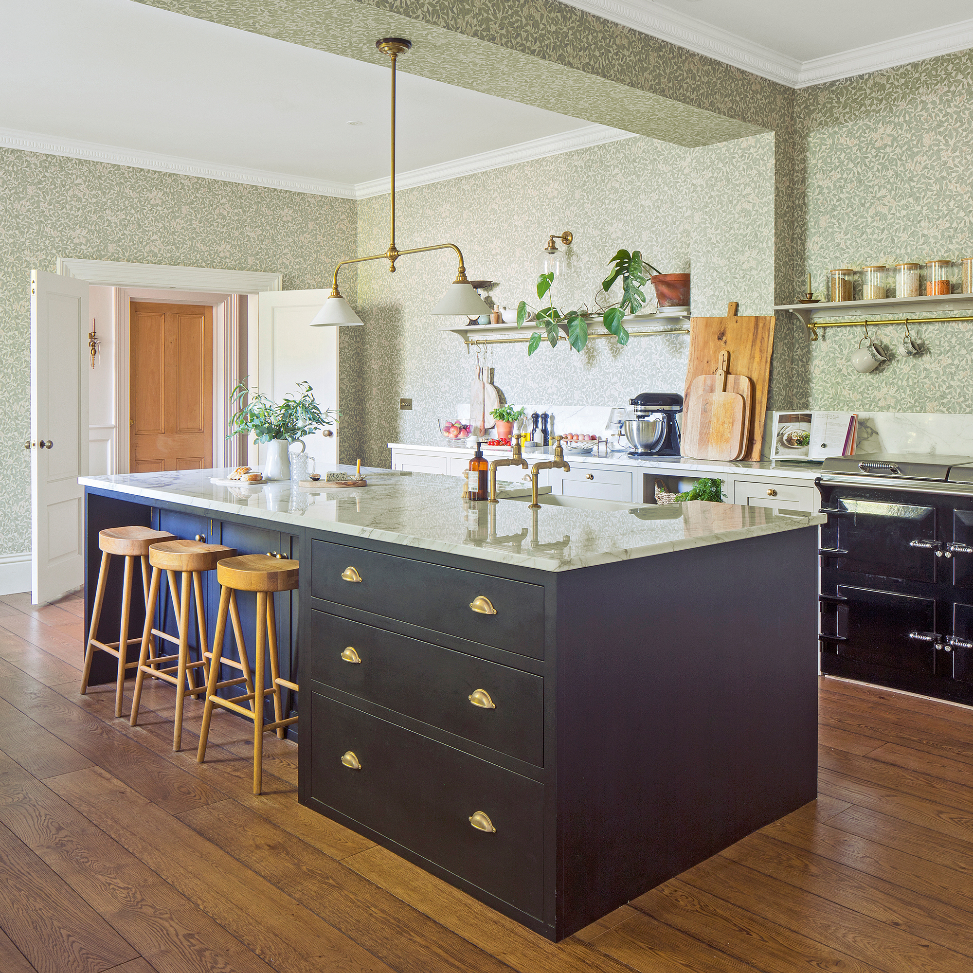 an open plan country-style kitchen with opening shelving, a black Aga and a kitchen island with three bar stools