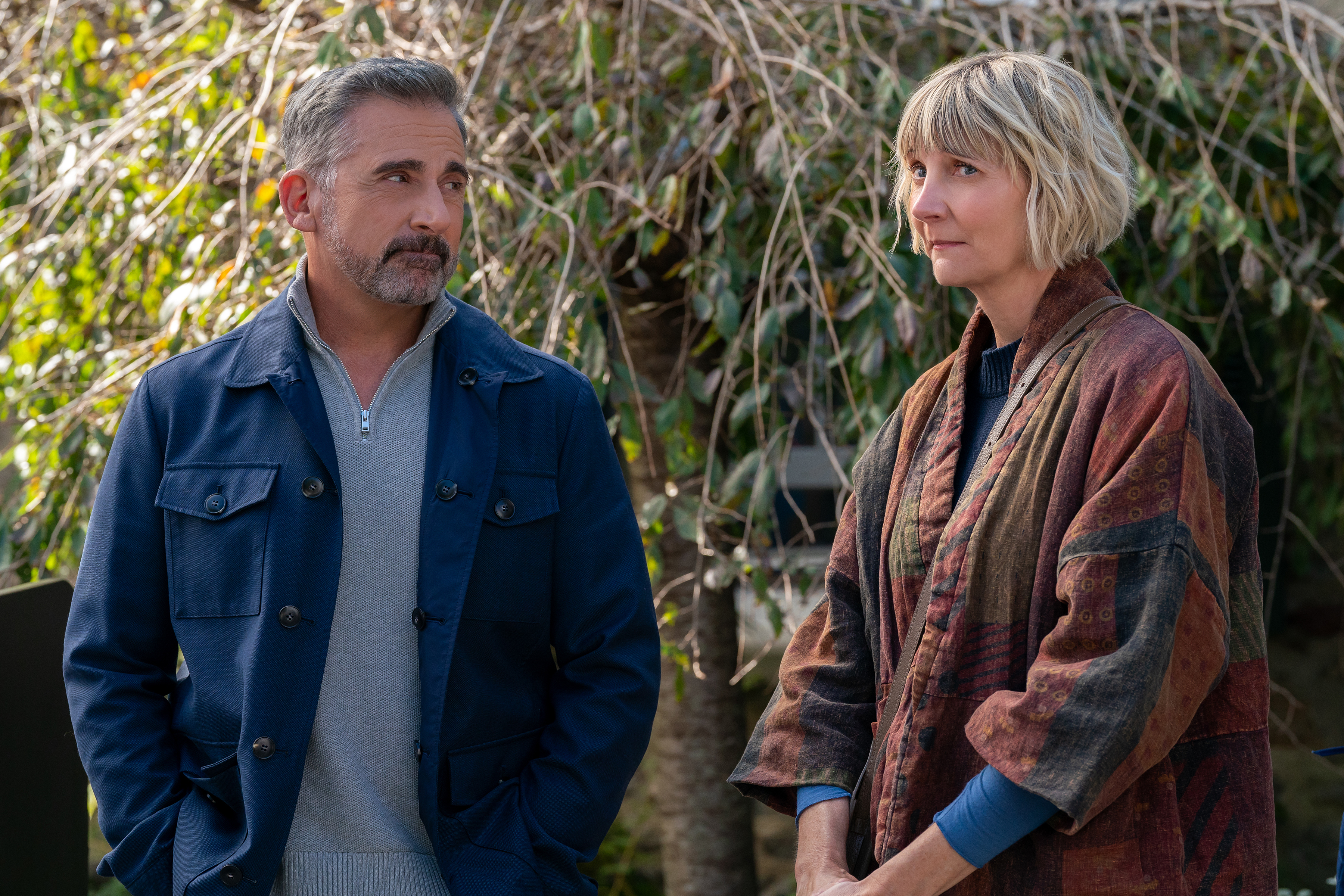 Two people (Steve Carell as Nick and Kerri Kenney as Anne) stand in front of foliage and a white fence, in Episode 106 of The Four Seasons.