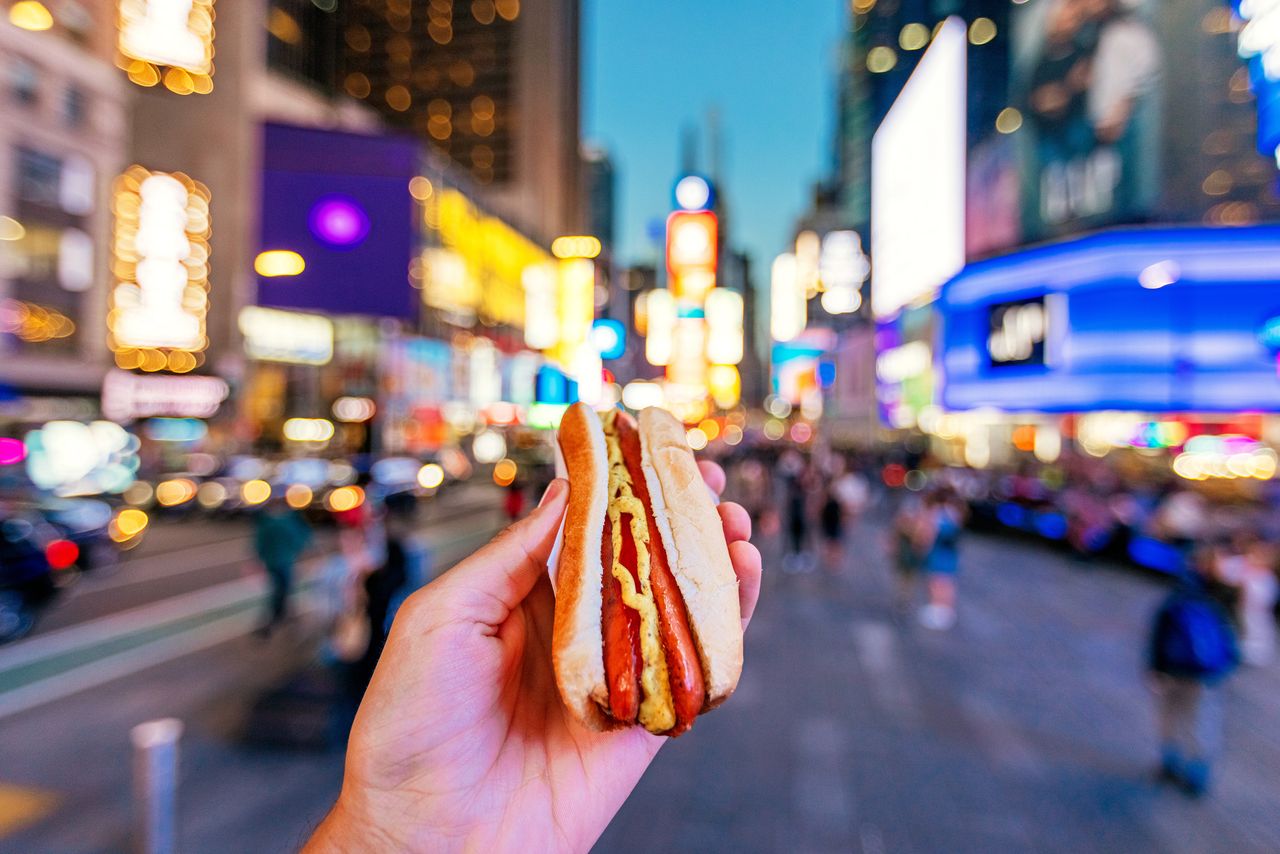 A person holding a hot dog on the streets of New York, USA