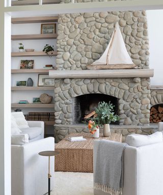 living room with stone fireplace and white armchairs