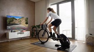 A woman using the Rouvy cycling simulator