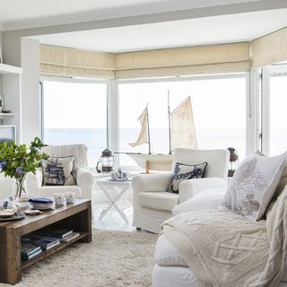 coastal house interior with glass window and blinds and white arm chair with cushions