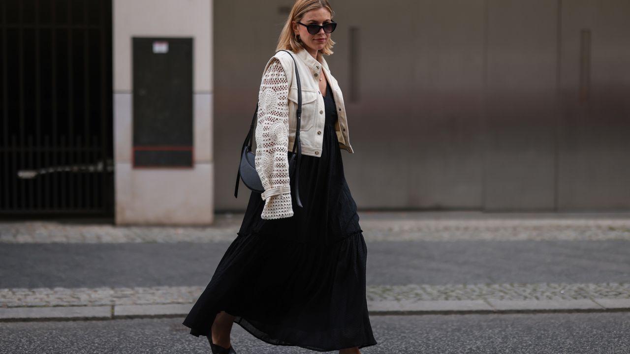 Aline Kaplan is seen wearing Polene Paris black round leather bag, Veronica Beard beige jeans jacket, Carolina Lemke black shades, Gestuz black maxi dress and Vagabond black sandals on May 25, 2022 in Berlin, Germany. 