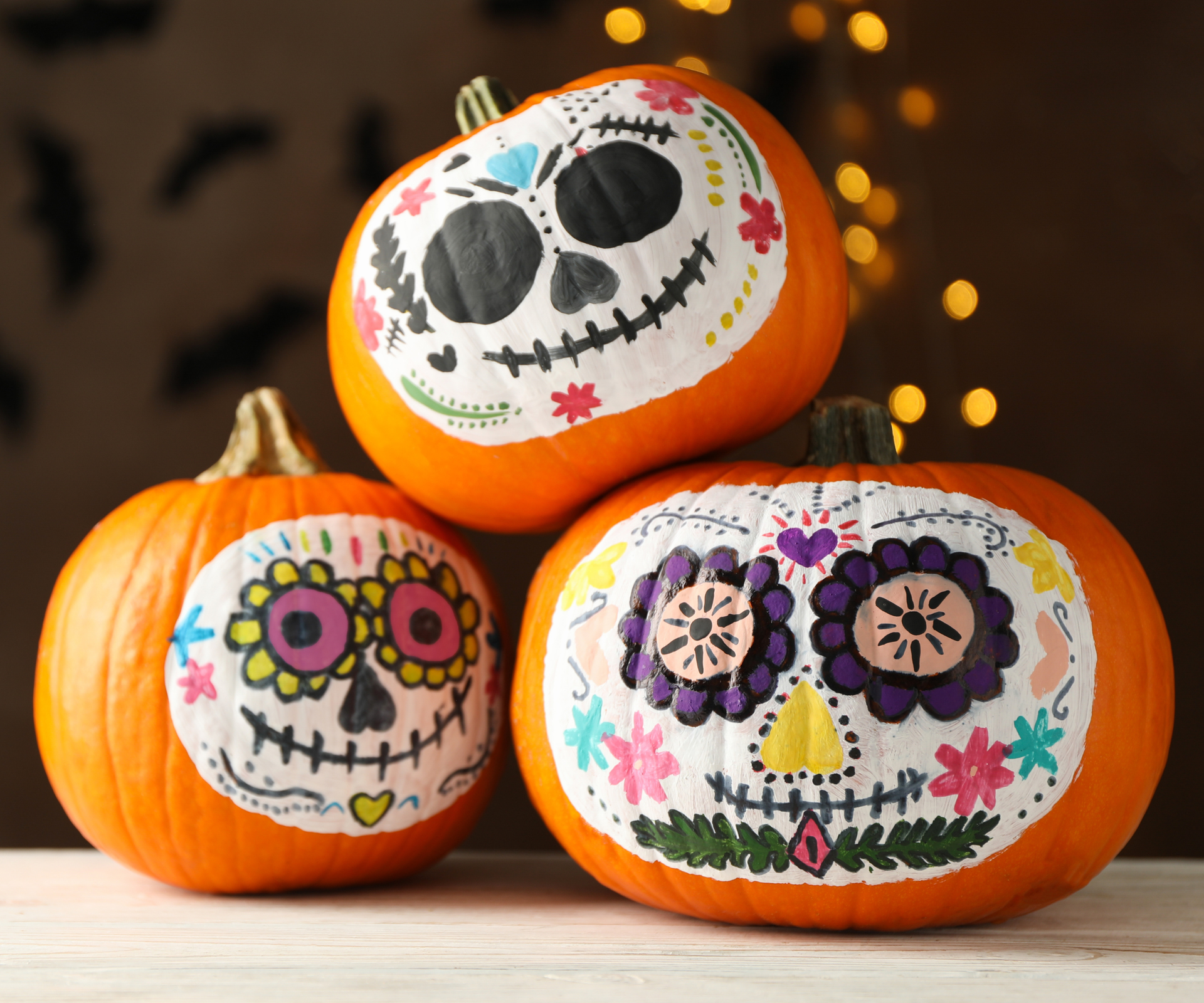 Pumpkins with catrina skull makeup on brown background with blurred lights