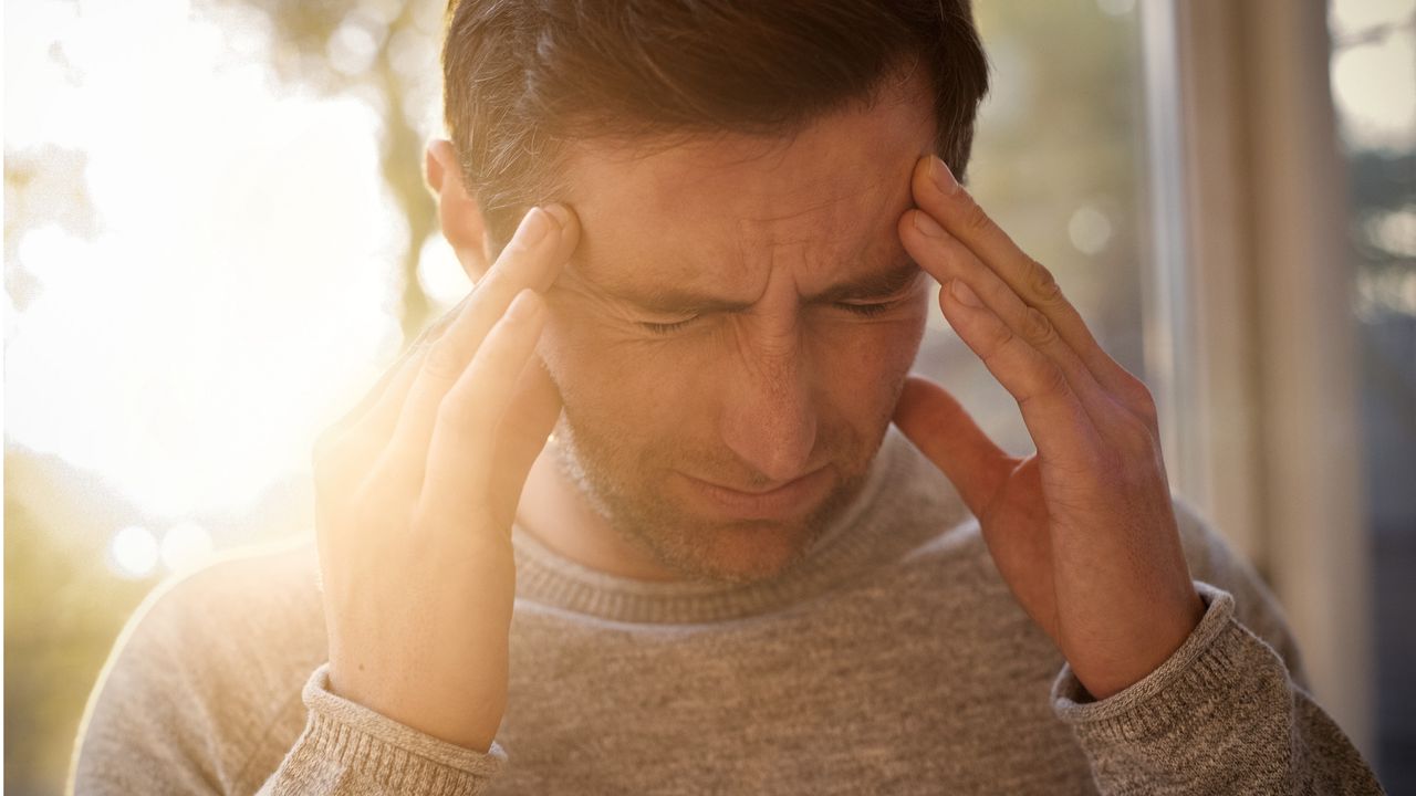 A man holds his temples like he has a bad headache.