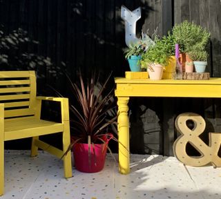 yellow patio set with exterior wood paint makeover and black painted fence