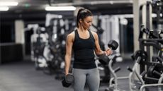 A woman doing dumbbell curls in the gym