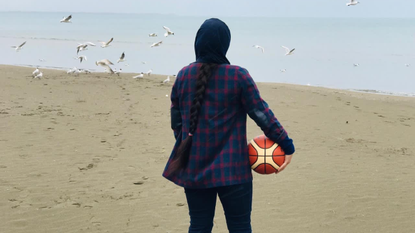 An Afghani basketball player looks out at the beach in Albania where she is living as a refugee