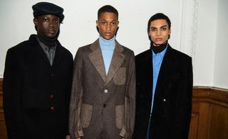 3 male models in thick coats looking posing for the camera