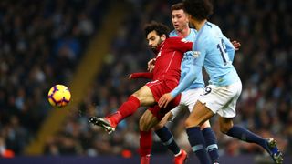 Liverpool's Mo Salah fends off two Manchester City players off while kicking the ball during a Premier League soccer match