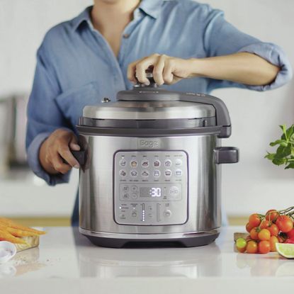 Woman in a blue blouse using the age The Fast Slow Go multi-cooker