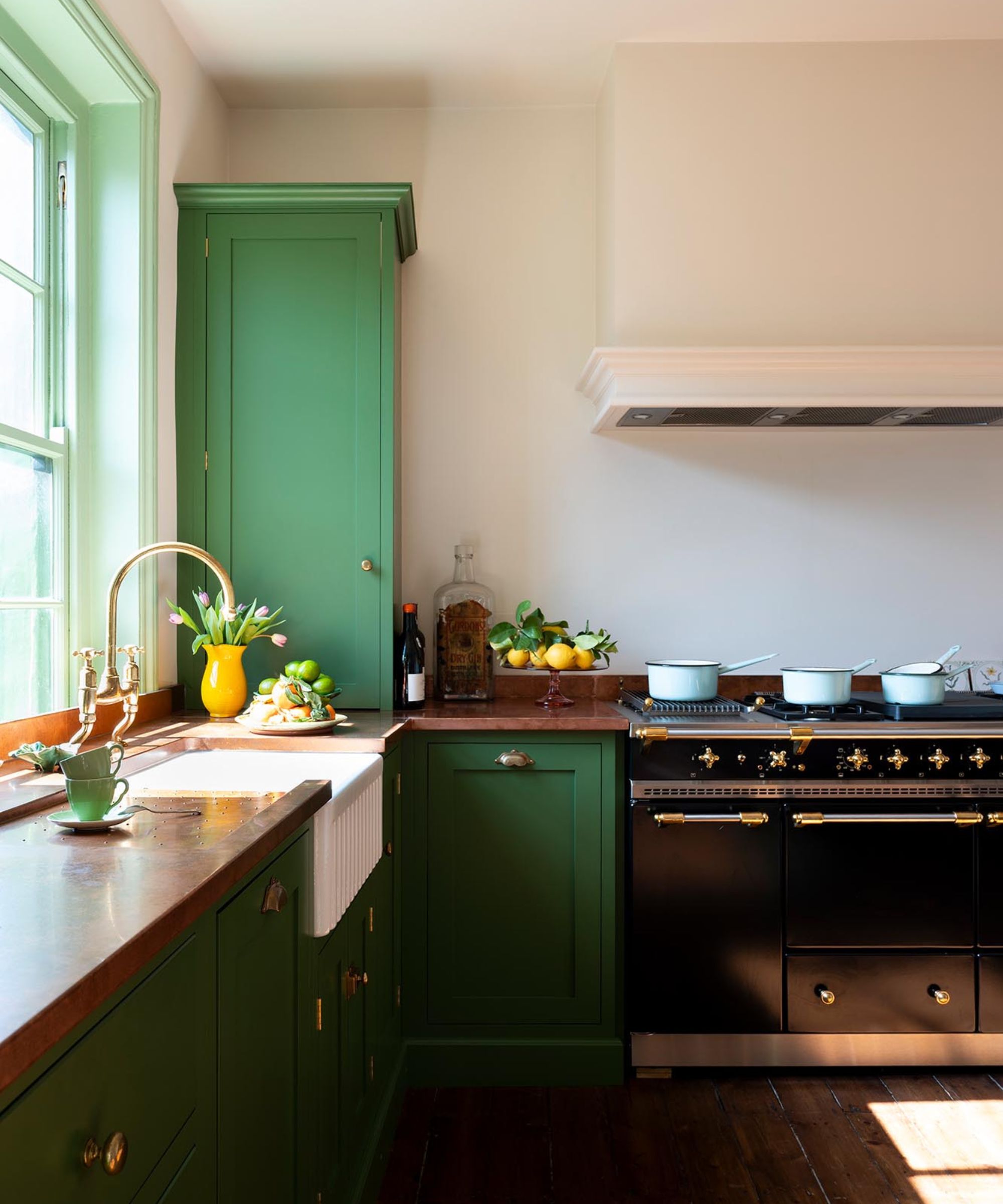 A small green kitchen with copper countertops and one full length countertop cabinet to hide the boiler