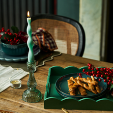 green twist candle in glass candle holder on a wooden table with linen cloth