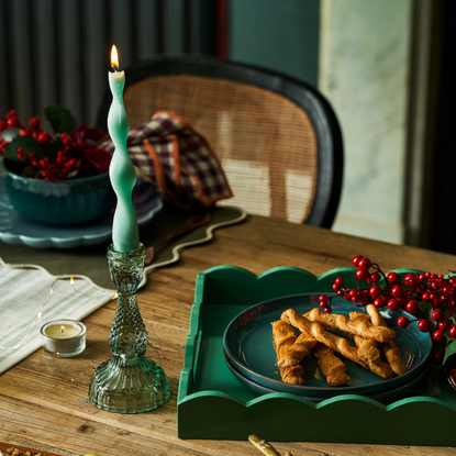 green twist candle in glass candle holder on a wooden table with linen cloth