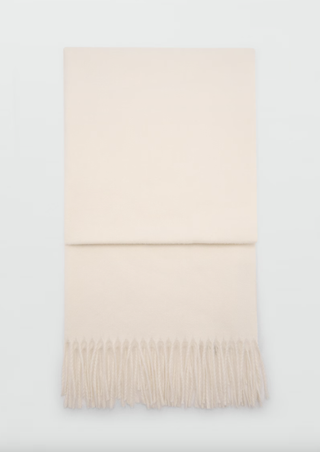 a mango fringe scarf in front of a plain backdrop