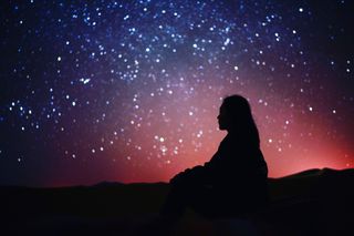 Woman Sitting Against Sky At Night