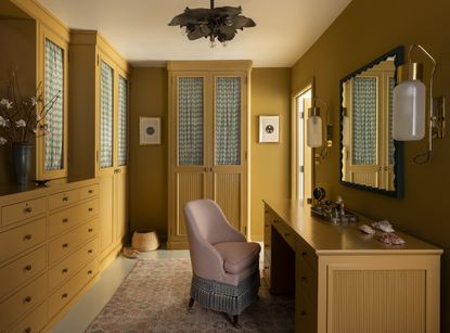 a yellow closet with vanity and yellow cabinets with curtains inside the door