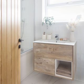 white bathroom with wooden vanity unit and wooden door